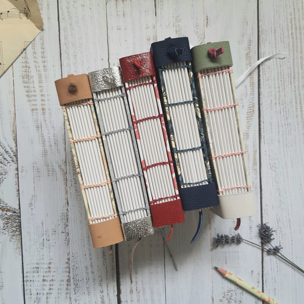 Coptic stitch notebooks with floral covers and leather details.